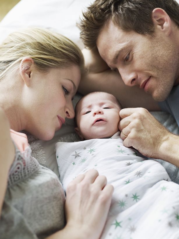 Parents avec bébé sur un lit