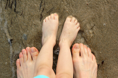 deux paires de pieds debout sur le sable