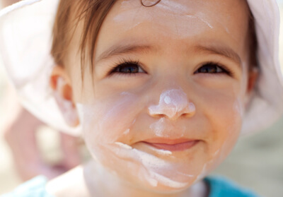 une petite fille avec un écran solaire sur son visage