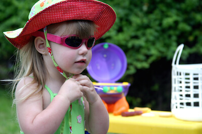 une petite fille portant un chapeau et des lunettes de soleil