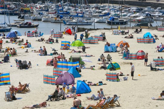 Météo britannique. Les sunbathers affluent vers la plage de la station balnéaire de Lyme Regis dans le Dorset pour profiter d'une journée de ciel bleu et ensoleillé