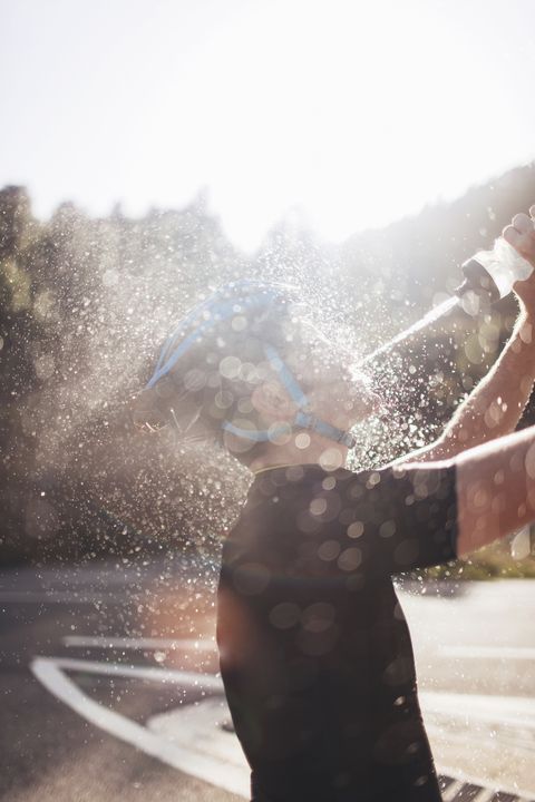 Vue latérale du cycliste pulvérisant de l'eau sur le visage en journée ensoleillée