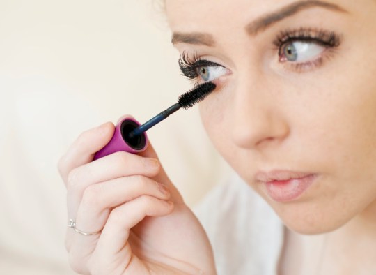 Jeune femme européenne se maquillant de mascara sur ses cils
