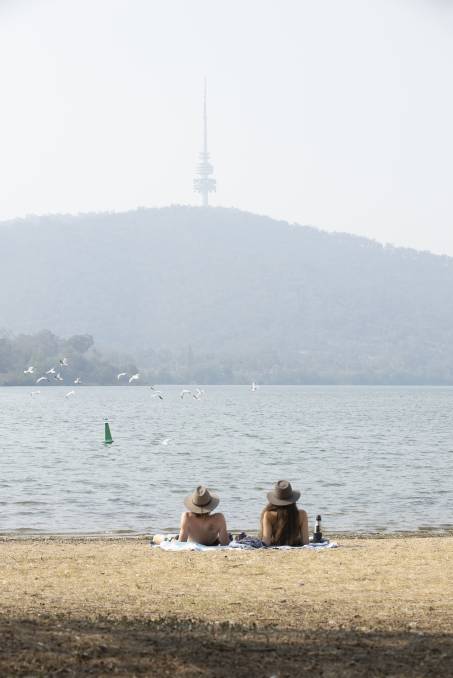 Aaron Long de Port Macquarie et Friederike Bock d'Allemagne ont passé lundi après-midi au bord du lac à Yarramlumla alors qu'une brume de fumée obscurcissait Black Mountain en arrière-plan. Image: Sitthixay Ditthavong