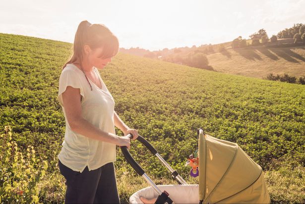 Une mère s'occupe de son enfant dans un landau par une journée ensoleillée